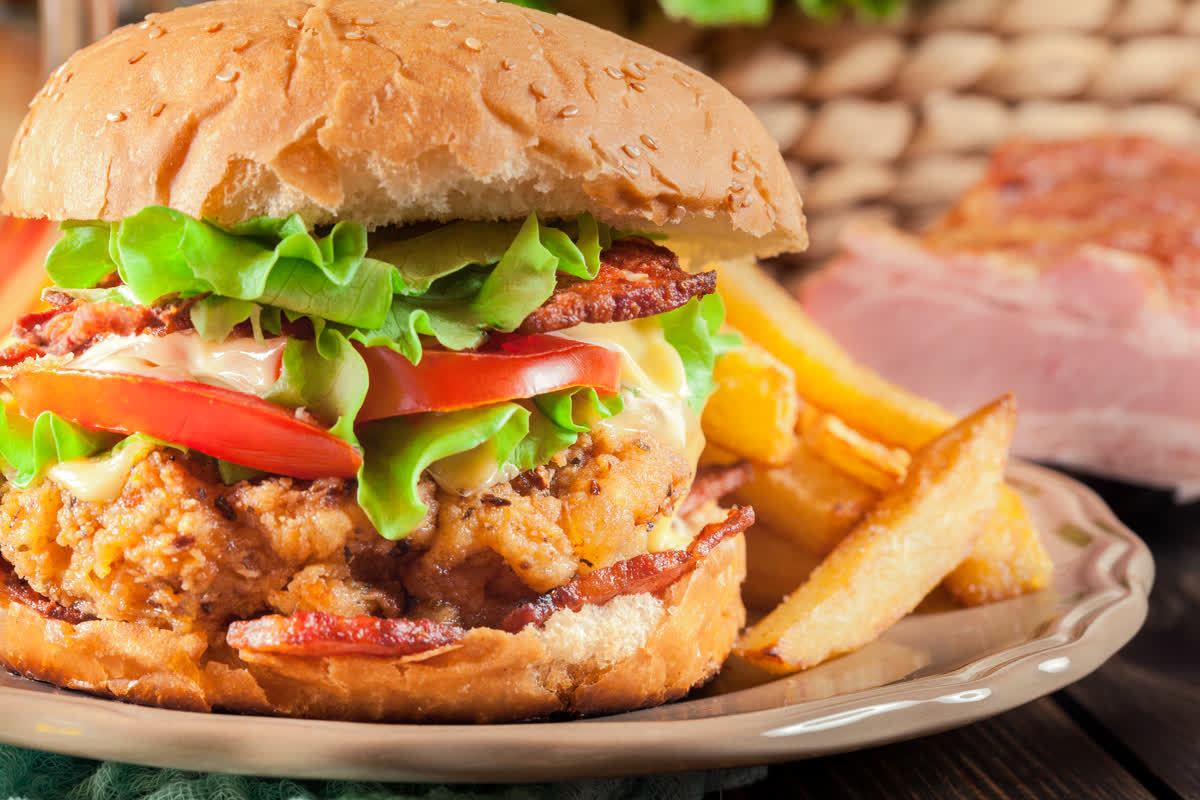 Fried chicken sandwich with lettuce, tomato, and fries